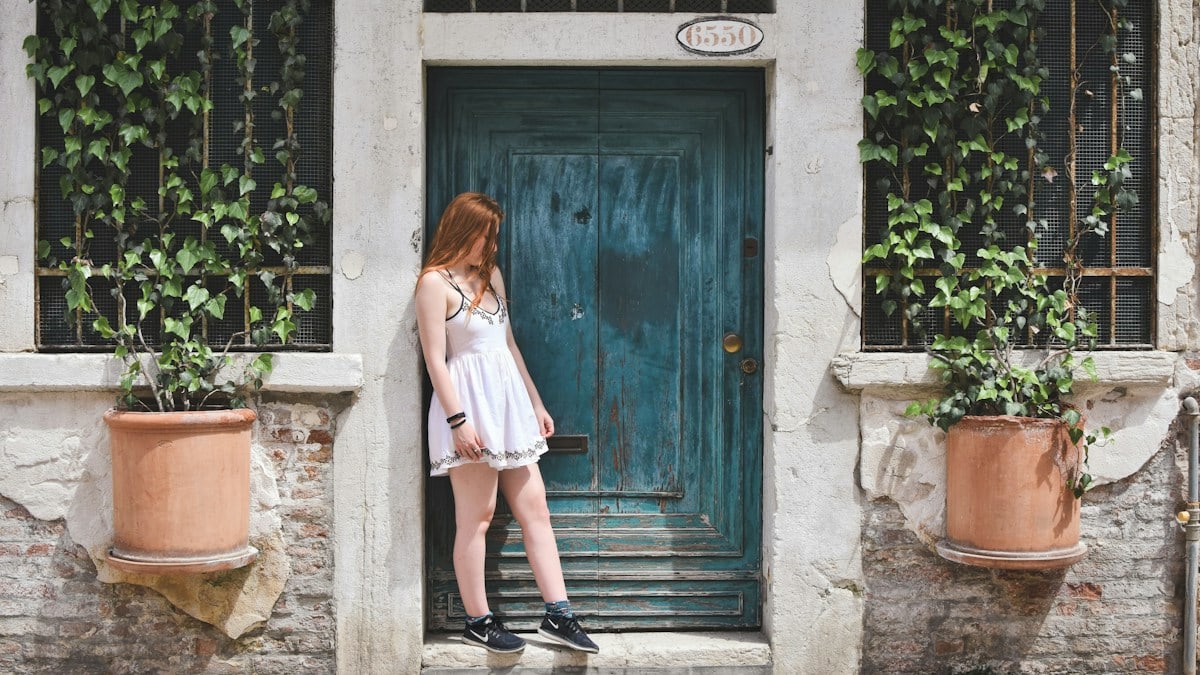 woman leaning on wall during daytime